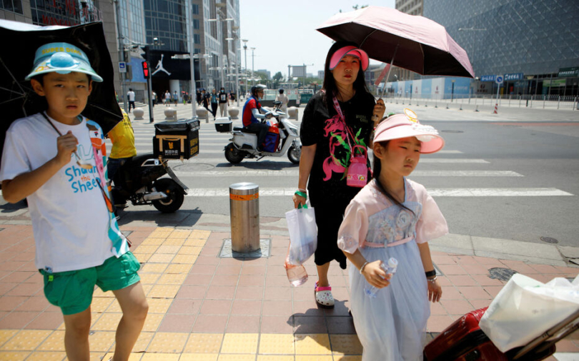 People wearing sun-protective caps walk in the sun on a hot day amid an orange alert for heatwave, in Beijing, China June 16, 2023. REUTERS/Flonrece Lo